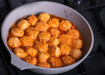 Cooking, meatballs in a pan with tomato sauce.