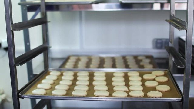 Process of making macaron, Cook puts trays of macarons