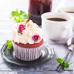 Dessert for Valentines Day, beautiful red velvet cupcake decorated with pink rose on old white wooden background.