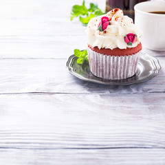 Dessert for Valentines Day, beautiful red velvet cupcake decorated with pink rose on old white wooden background with copy space.