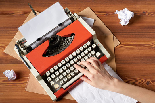 woman hand typing on red vintage typewriter