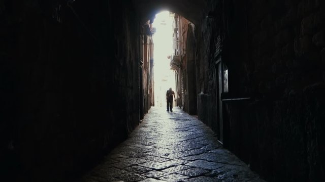 Silhouette of Elder walks In the alleys of the center of Naples, Italy