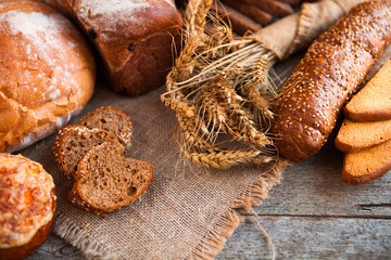 Assortment of fresh baked bread on wooden table background