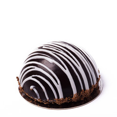 Hemispherical chocolate cake with white decoration isolated