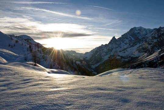 Il sole scende dietro alle vette del monte Bianco creando una magica raggiera.