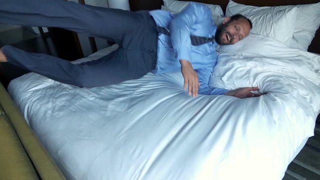 Young businessman jumping, falling on bed, super slow motion 240fps
