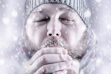 Freezing cold man  snow storm storm white out trying to keep warm by blowing into his hands....