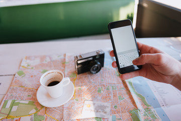 Man by the table with map, phone, coffee and camera
