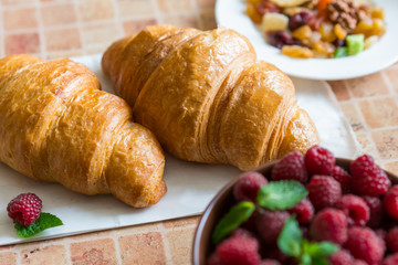 Croissants and raspberries on the table.