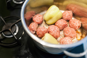 Cooking of meatballs and filled paprika in a bowl.