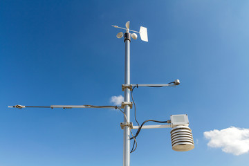 Anemometer, temperature and humidity meteorological instrument on the pole against the clear blue...