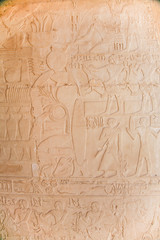 stone wall of egyptian temple with carved hieroglyphs, with ceremony procession of people with animals and food, in Egypt, Africa
