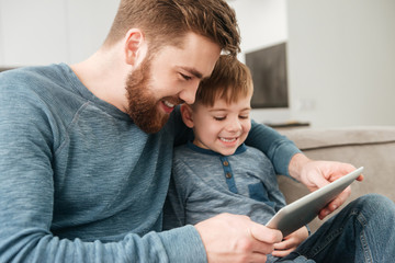 Father using tablet computer with his little cute son.