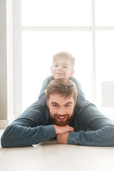 Cheerful boy lies on the floor with his bearded father