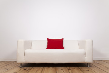 Sofa mit roten Kissen und weißer Wand