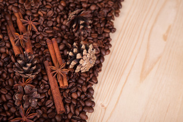 seasoning cinnamon (Cinnamomum) and anise (Anisium vulgare Gaerto) lies on the coffee beans among Christmas pine cones, background, close-up, a place for an inscription, wooden surface