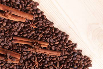 seasoning cinnamon (Cinnamomum) and anise (Anisium vulgare Gaerto) lies on the coffee beans among Christmas pine cones, background, close-up, a place for an inscription, wooden surface