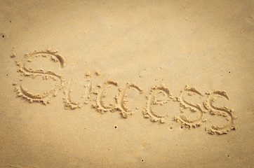 Success words hand writing on sand beach texture background.