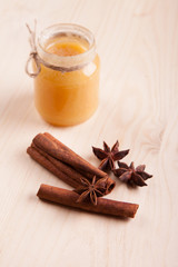 Fototapeta na wymiar Honey in a glass jar and condiment cinnamon (Cinnamomum) and anise (Anisium vulgare Gaerto) lies on a light wood surface, background, close-up, a healthy lifestyle