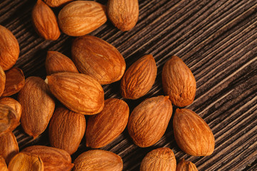 Apricot kernels are scattered on the wooden background