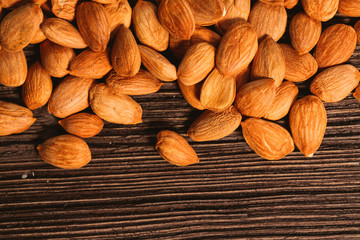 Apricot kernels are scattered on the wooden background