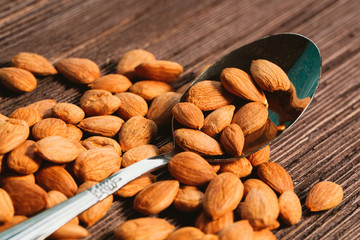apricot kernels sprinkled with metal spoon on a wooden background