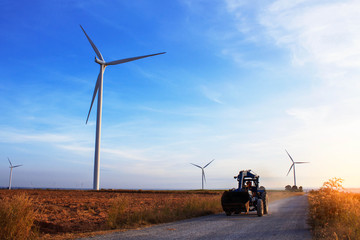 tractors on a rural road with a wind farm.