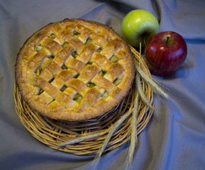 Apple pie on a wicker plate on gray background