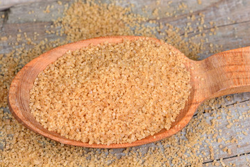 Beige sugar in a wooden spoon