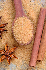 Beige sugar in a spoon and anise star with cinnamon