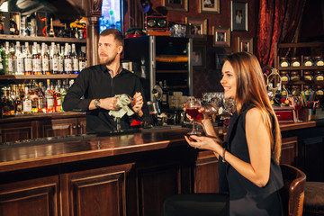 beautiful young woman sitting at the bar talking with the bartender