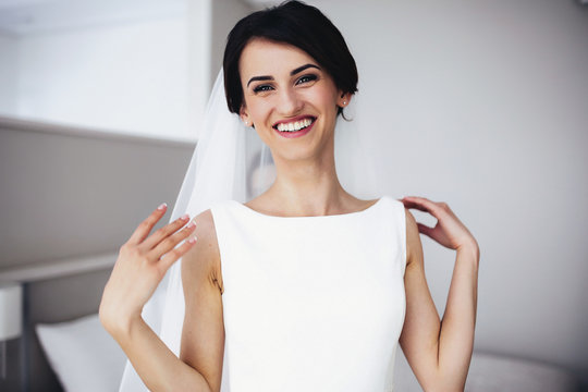 The smailling bride stands in the center of room