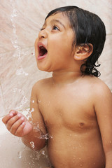 Naklejka premium Happy baby in the bath, drinking water from shower