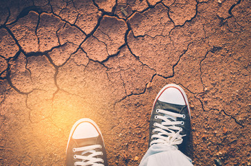 Top view of shoes and blue jean on dry crack soil texture background.