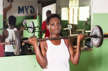 Young athlete, weight lifted at chest level looks at the camera.