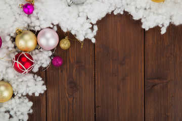 Colored christmas balls and snow decoration on wooden background