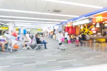 Defocused passenger in airport corridor with walking travelers
