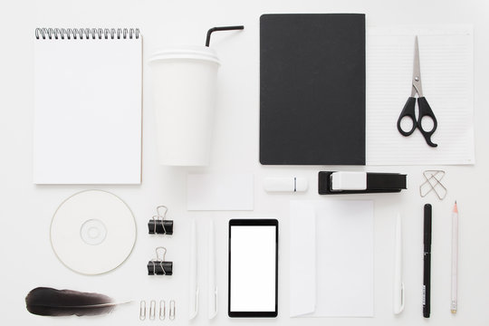 Black and white office stuff collection flat lay. Top view on set of stationery with smartphone and coffee to go paper cup. Modern life, communication, time-management, technologies concept
