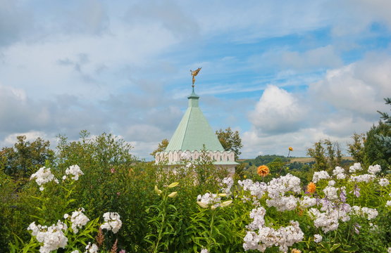 Chapel with a weather vane among the flowers in the Optina