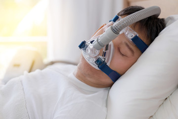 Sleep apnea therapy, Man sleeping in bed wearing CPAP mask.Healthy senior man sleeping deeply,...