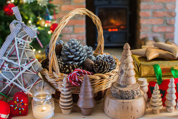 Diy Christmas: wooden toys, felt decorations, presents on the table, Christmas tree and fireplace with burning fire on the background, selective focus