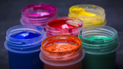 Bright multi-colored paint on black wooden background. for the artist. Education.