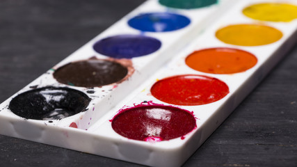 Bright multi-colored paint on black wooden background. for the artist. Education.