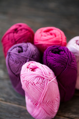 Different types of pink and purple yarn on a wooden background