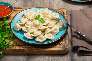 Ravioli with a red sauce on a wooden board