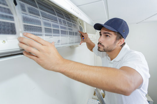 portrait of mid-adult male technician repairing air conditioner