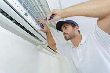 portrait of mid-adult male technician repairing air conditioner
