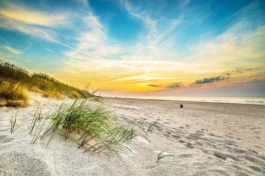 Fototapeta Wydmy na tle zachodzącego słońca na plaży w północnej Polsce
