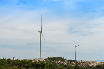 Fototapeta premium Wind turbine on the green grass over the blue clouded sky