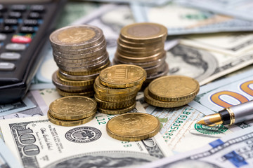 us coin on top dollar bills with pen and calculator.